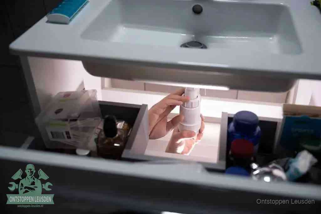 Een pompfles met zeep boven een wastafel, de heet water en afwasmiddel-methode om een vetprop in de afvoer los te maken in Leusden