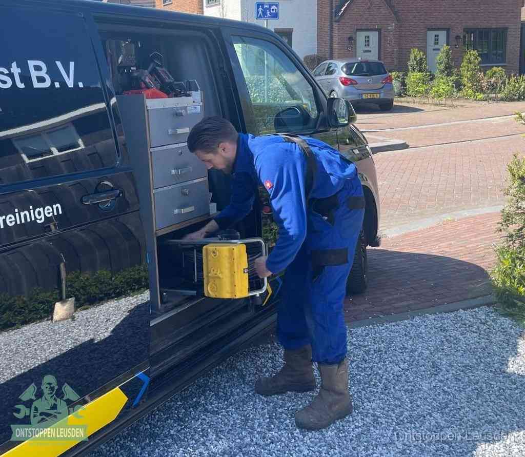 Een monteur pakt buiten op de oprit gereedschap uit de bedrijfsbus, het moment om een professional in te schakelen voor een verstopte afvoer in Leusden