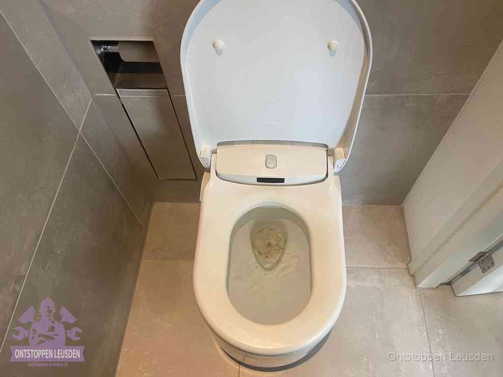 Een wit hangtoilet waarin een prop wc-papier op het water blijft drijven, een duidelijk signaal van een verstopte wc in Leusden