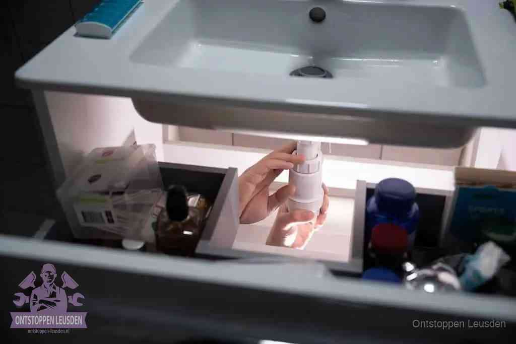Een pompfles met zeep boven een wastafel in de toiletruimte, de warm water en afwasmiddel-methode om de wc te ontstoppen in Leusden