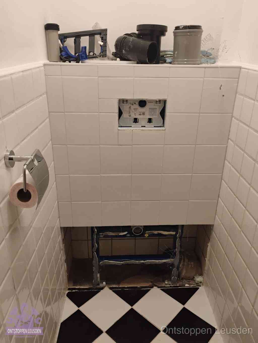 Een toiletruimte waar het hangtoilet en de inbouwreservoir-onderdelen zijn vrijgelegd voor onderhoud, periodiek nazicht voorkomt een wc-verstopping in Leusden